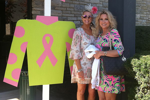 Cancer survivors standing next to wood cutout of jockey silk at Keeneland program.